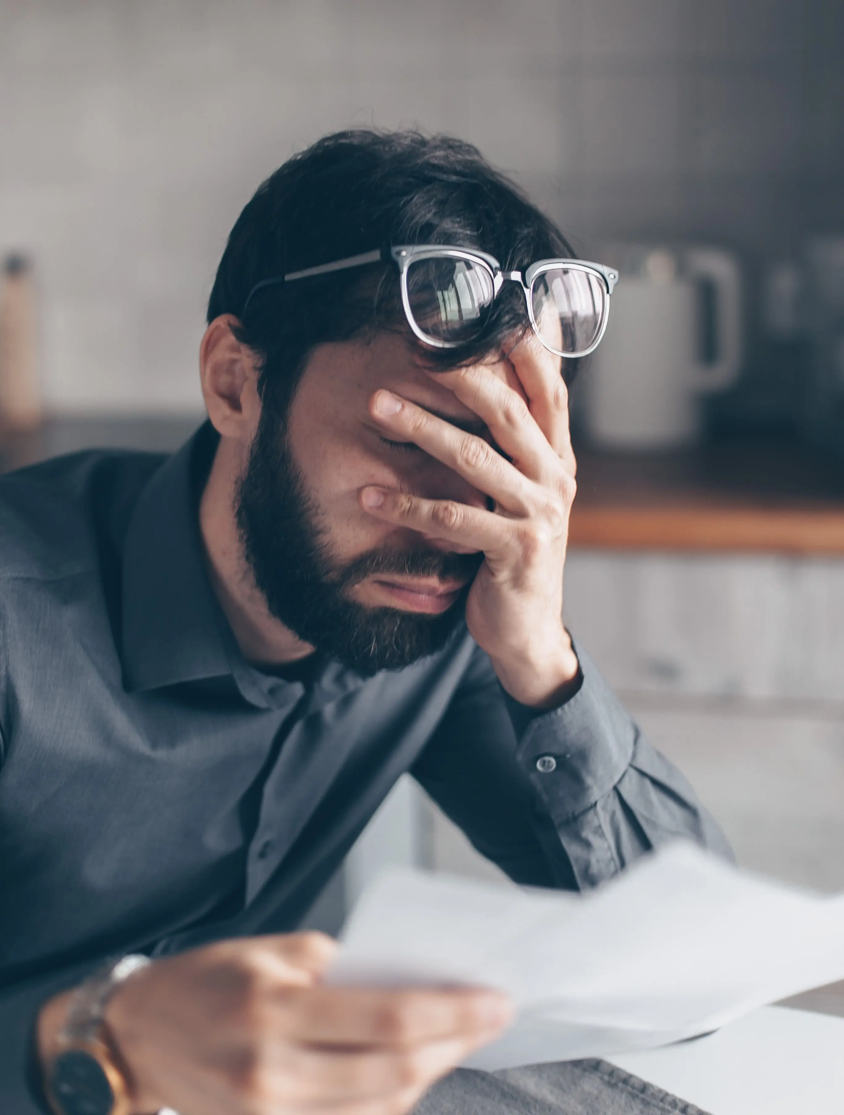 Stressed homeowner reviewing financial documents and foreclosure notices