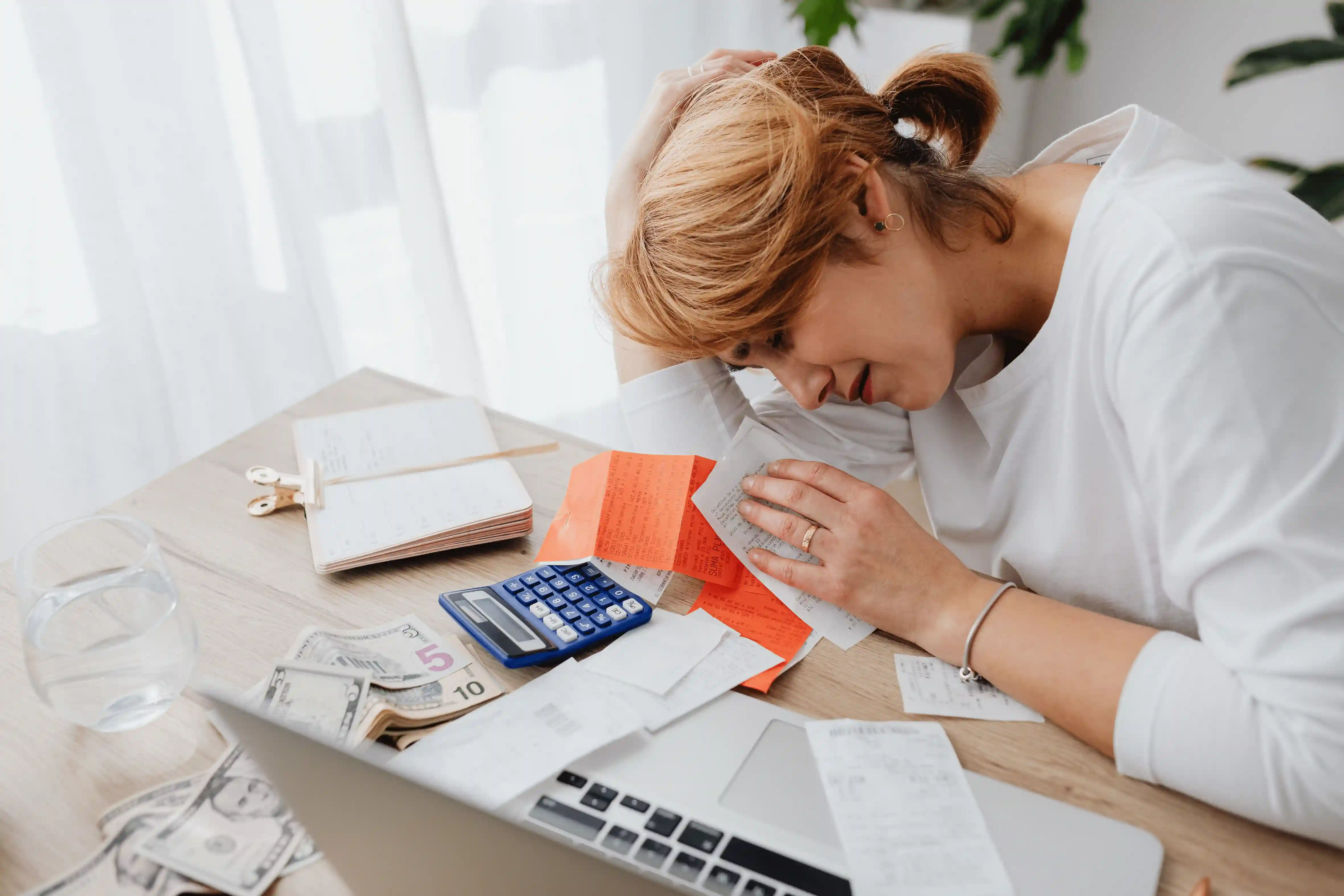 A frustrated homeowner reviewing delayed insurance claim paperwork at their kitchen table